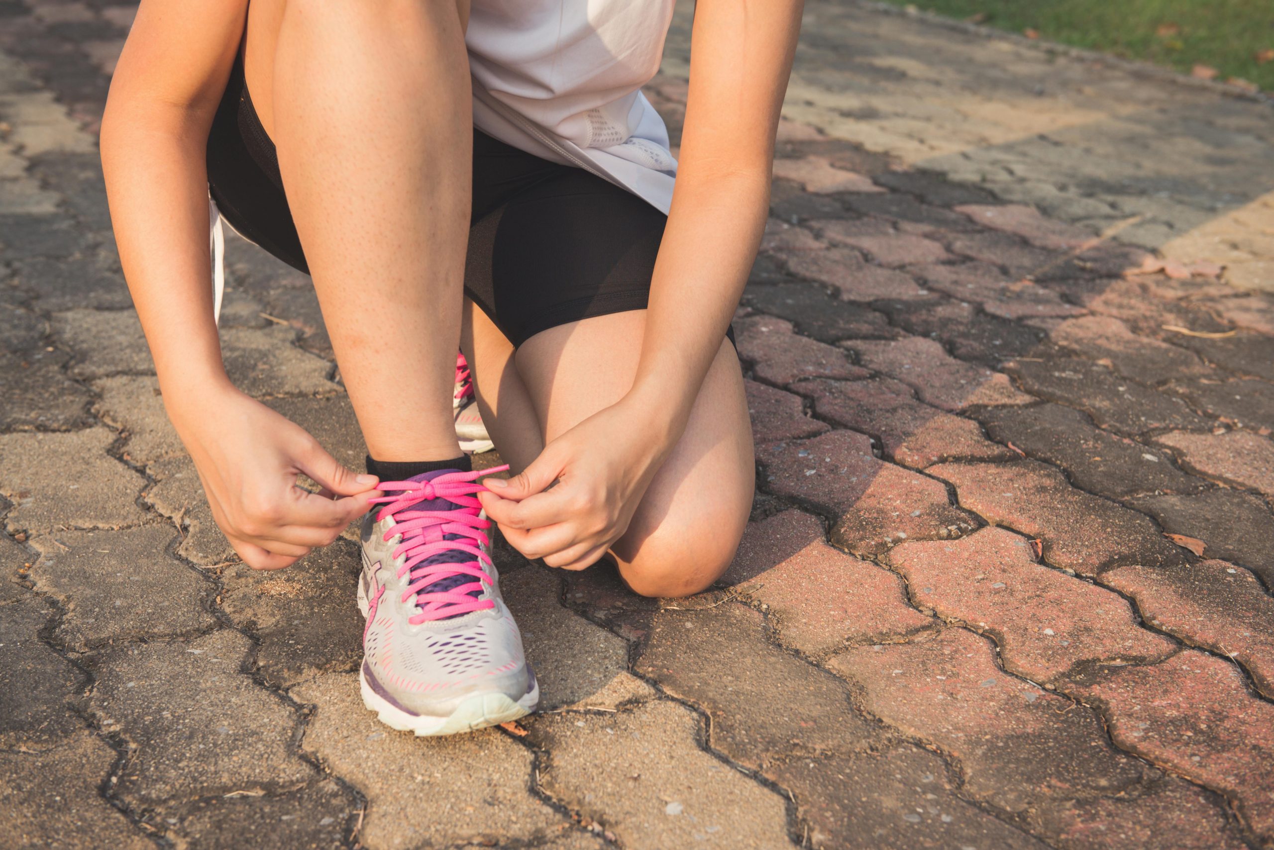 woman tying her shoes on the sidewalk