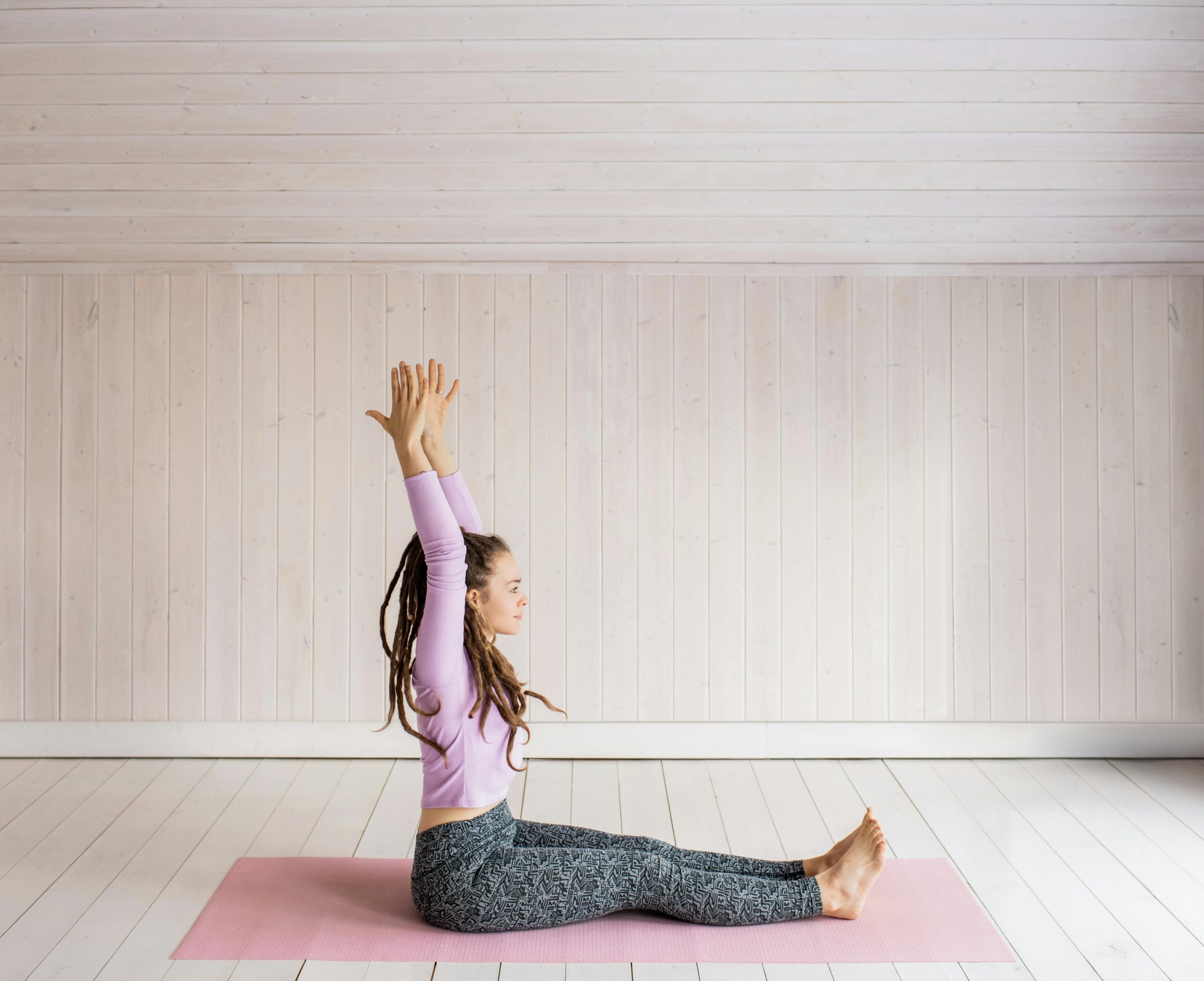 woman seated on a yoga mat, doing somatic stretching