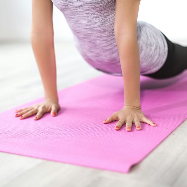 woman doing somatic exercises on a pink yoga mat